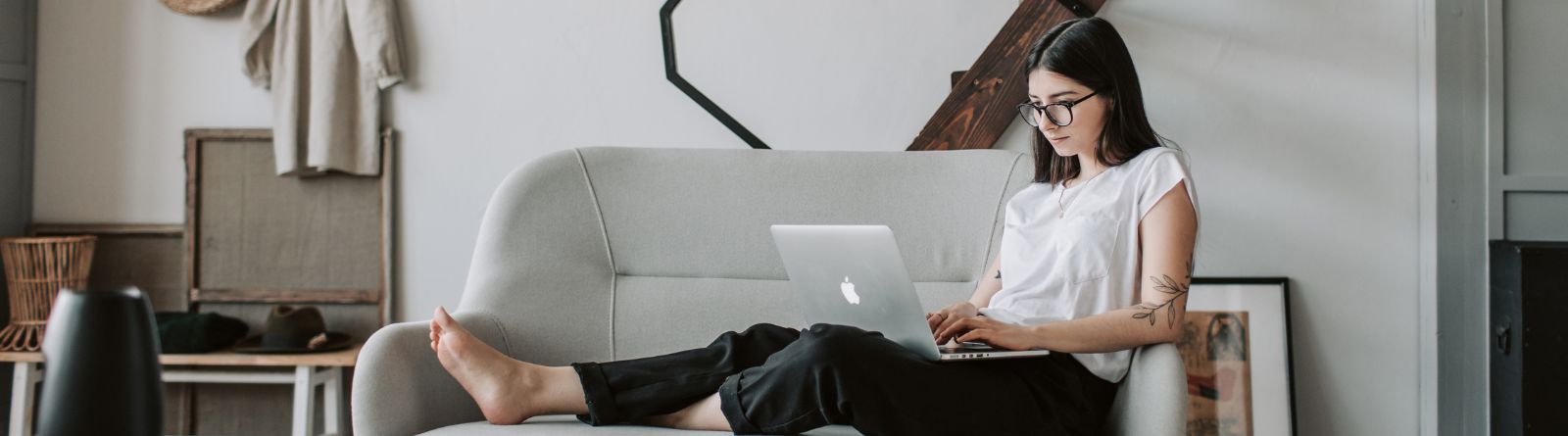 A young woman sitting on the couch with a laptop